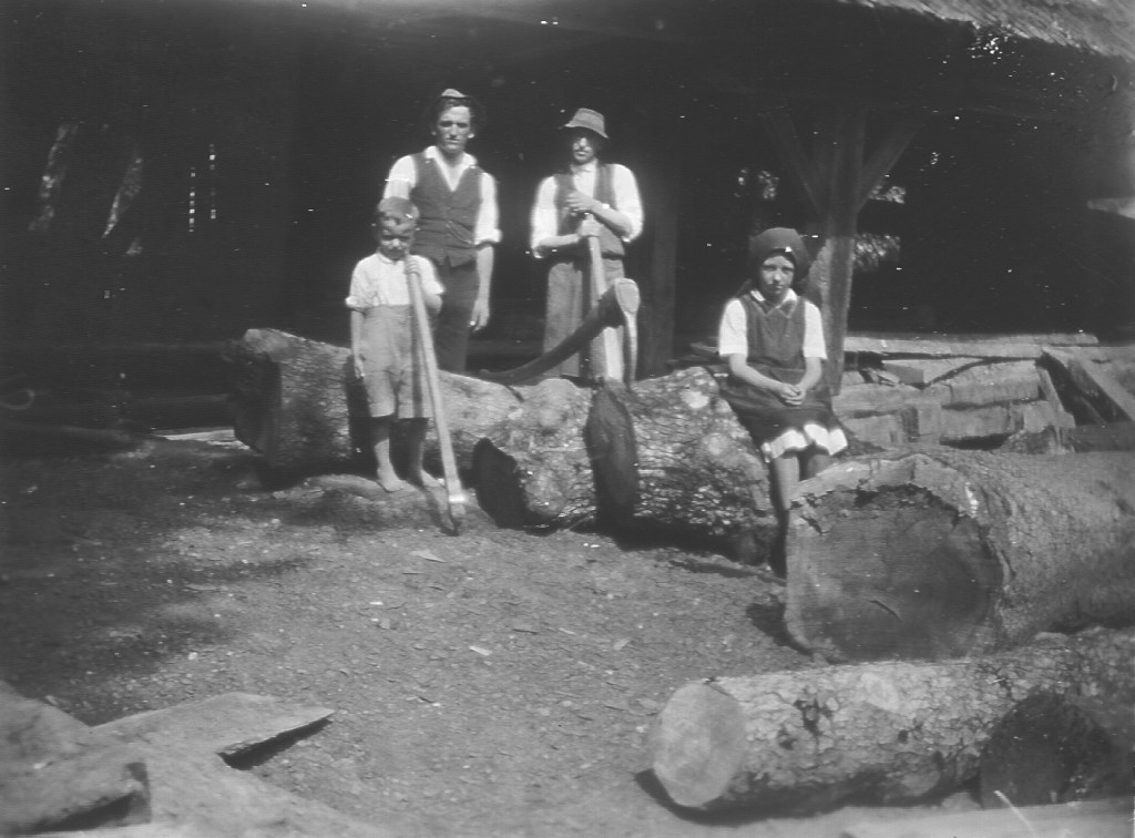 Old black and white photograph of family by tree trunks