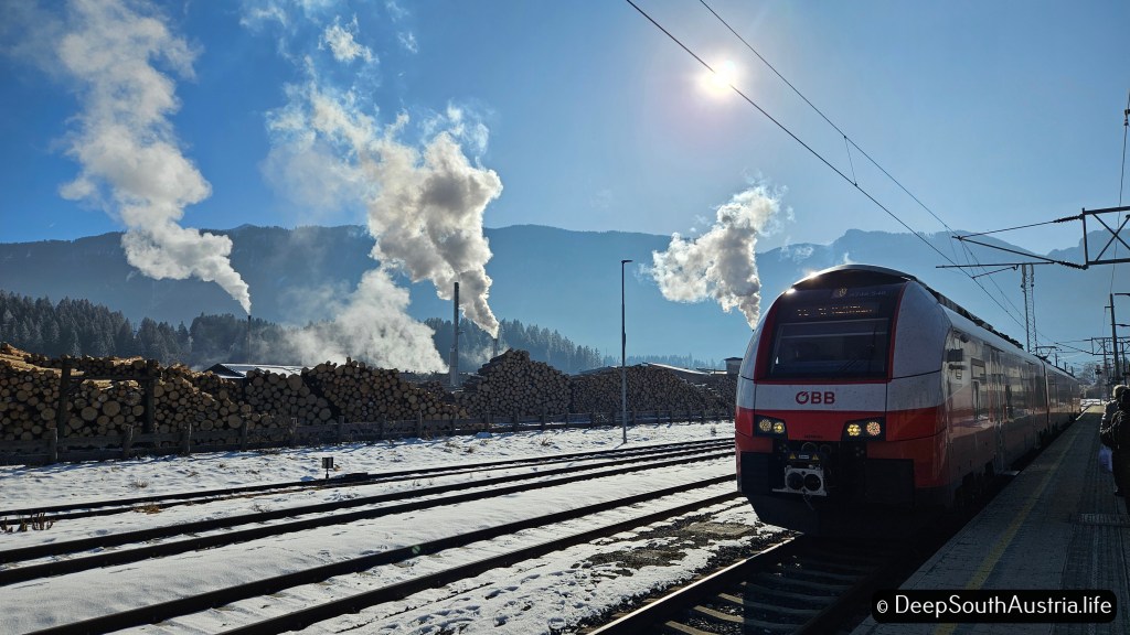 Steam rises from a lumber yard in Hermagor as the train waits in the station, Gail Valley, Austria